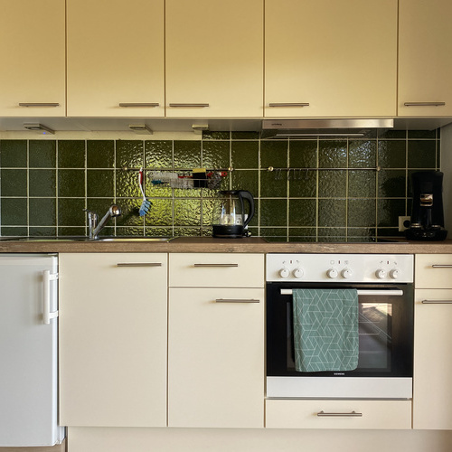 Küchenzeile mit Kühlschrank, Herd, Backofen, Kaffeemaschine und Oberschränken - 